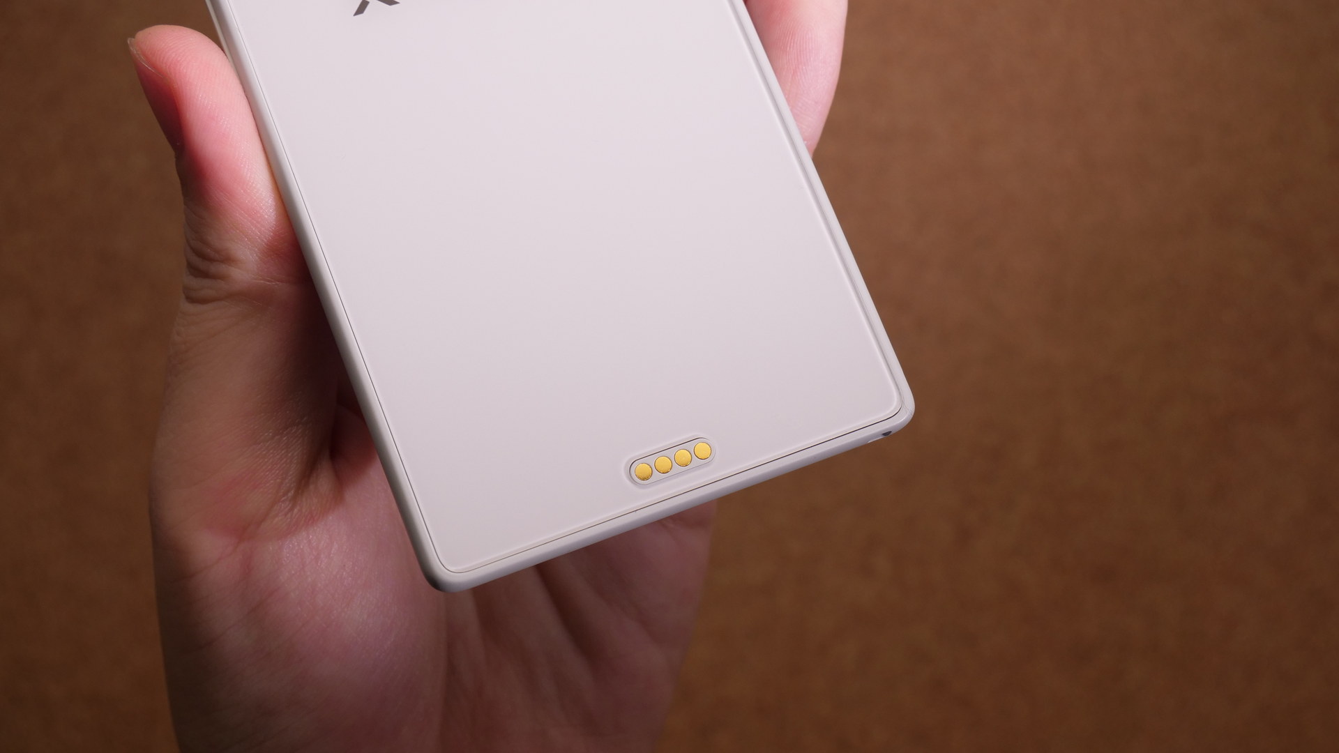 Xteink X3の背面下部にある金色のポゴピン式充電端子を手に持って写した写真