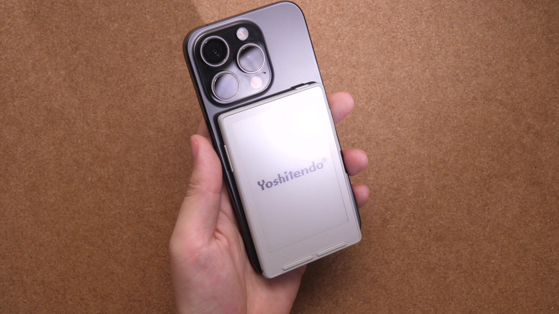 Xteink X3をスマートフォンの背面にマグネットで貼り付け、片手で持って画面を見ている写真